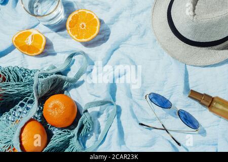 Picknick-Flatlay von Orangen in einer Öko-Saite und hut auf blauer Decke Stockfoto