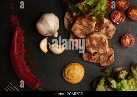Medaillons von Fleisch auf einem Steingrund mit Gemüse und Kräuter aus nächster Nähe Stockfoto