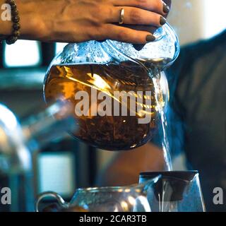 Traditionelle Chinesische Teezeremonie. Schwarzer oder roter Tee Gießen aus Glas große Teekanne in Glas Chahai auf dunklen Holztisch Hintergrund Stockfoto