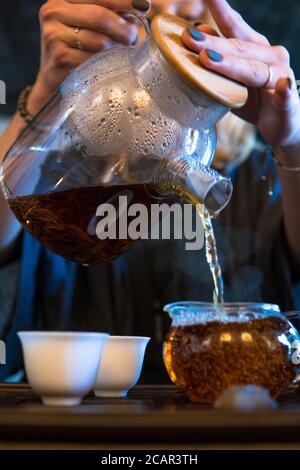 Traditionelle Chinesische Teezeremonie. Schwarzer oder roter Tee Gießen aus Glas große Teekanne in Glas Chahai auf dunklen Holztisch Hintergrund Stockfoto
