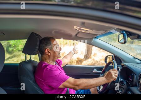 Profilansicht eines älteren Mannes Mitte 60 am Lenkrad eines Autos. Stockfoto