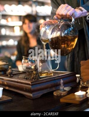 Traditionelle Chinesische Teezeremonie. Schwarzer oder roter Tee Gießen aus Glas große Teekanne in Glas Chahai auf dunklen Holztisch Hintergrund Stockfoto