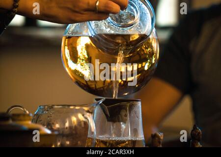 Traditionelle Chinesische Teezeremonie. Schwarzer oder roter Tee Gießen aus Glas große Teekanne in Glas Chahai auf dunklen Holztisch Hintergrund Stockfoto
