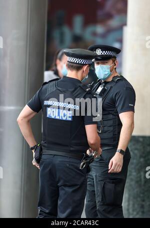 Britische Polizisten tragen Gesichtsmasken wegen der Coronavirus-Pandemie. Stockfoto