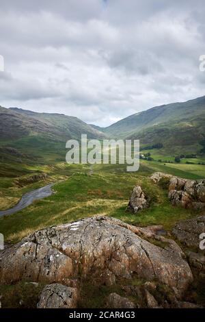 Die Straße, die vom Hardknott Pass in Cumbria, Großbritannien, zum Wrynose Pass führt, durch den Lake District National Park, der von Osten nach Westen führt Stockfoto