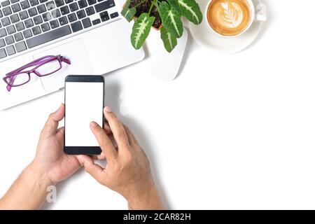 Hand Mann Touch auf weißem Bildschirm Smartphone mit Laptop und Kaffee isoliert auf weißem Hintergrund, Draufsicht und Business-Konzept Stockfoto