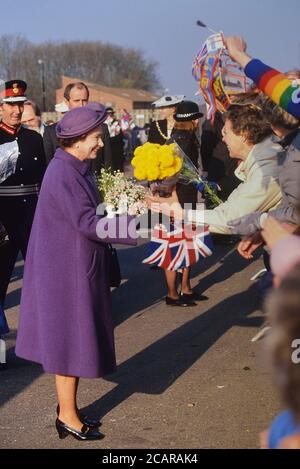 Ein lächelndes HM Queen Elizabeth II in einem lila Outfit begrüßt die Verehrer vor dem NSCC Training Headquarters in Beaumont Leys, Leicester, Leicestershire, England, Großbritannien. Ca. 1980 Stockfoto