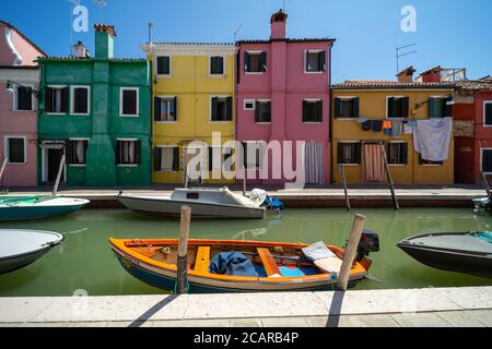 Burano Insel, Lagune von Venedig, Venedig, Italien, Panorama mit den typischen farbigen Häusern Fronten auf einem Kanal und einem kleinen Boot in der Innenstadt Stockfoto