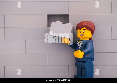 Tambow, Russische Föderation - 07. Juni 2020 Lego Geschäftsfrau Minifigur mit Ziegel bereit, die graue Wand zu beenden. Stockfoto