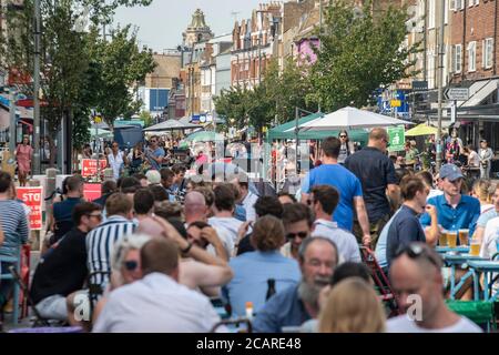 Clapham wartet auf Tische mit einer Gesichtsmask an der Northcote Road und ist nun für Autos gesperrt und öffnet an einem heißen Sommertag die Straße für Restaurants und Bars. Stockfoto