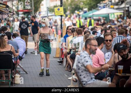 Clapham wartet auf Tische mit einer Gesichtsmask an der Northcote Road und ist nun für Autos gesperrt und öffnet an einem heißen Sommertag die Straße für Restaurants und Bars. Stockfoto