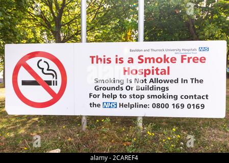 Schild vor Basildon Hospital, Essex, Großbritannien. Dies ist ein rauchfreies Krankenhaus. Rauchen ist auf dem Gelände oder in den Gebäuden nicht erlaubt. Kein Rauchen. NHS-Helpline Stockfoto