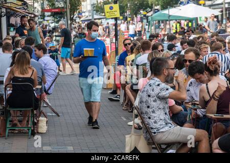 Clapham wartet auf Tische mit einer Gesichtsmask an der Northcote Road und ist nun für Autos gesperrt und öffnet an einem heißen Sommertag die Straße für Restaurants und Bars. Stockfoto