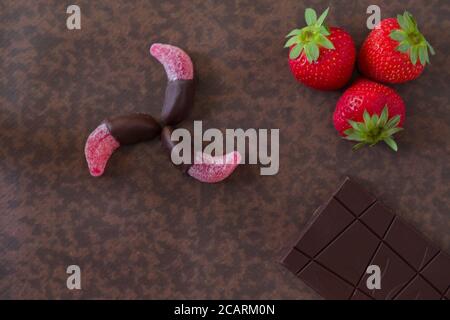Obstbonbons in Schokolade getaucht, zusammen mit einer Tafel Schokolade und Erdbeeren. Stockfoto