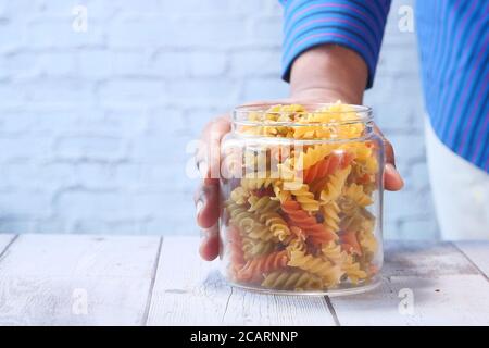 Mann Hand hält ein Glas trockene italienische Pasta Stockfoto