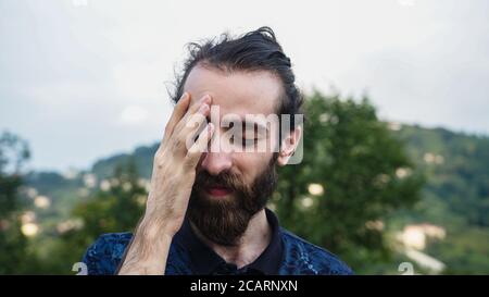 Hipster Mann mit langen Haaren und Bart leiden Kopfschmerzen Sieht traurig aus Stockfoto