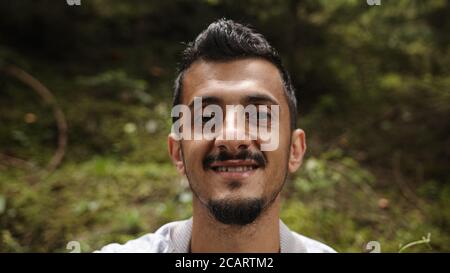 Porträt von jungen gut aussehenden bärtigen Brünette Mann Blick auf die Kamera Und lächelnd Stockfoto
