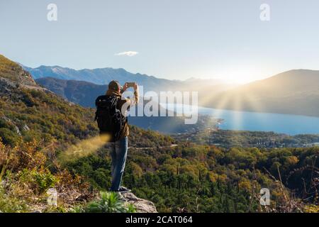 Reisende mit Rucksack und Smartphone steht auf einem Berg Stockfoto