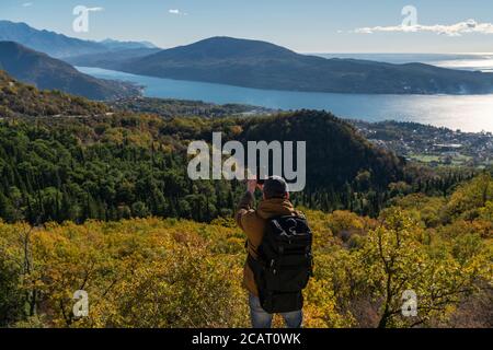 Reisende mit Rucksack und Smartphone steht auf einem Berg Stockfoto