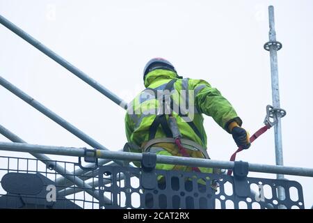 Gerüstarbeiter, der die Zugangsstruktur auf der Baustelle demontiert Stockfoto