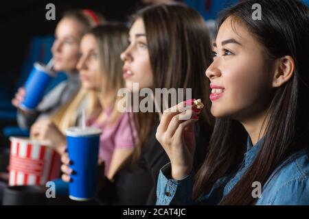 Lieblingsbeschäfdung. Schöne junge asiatische Frau lächelnd fröhlich essen Popcorn Filme mit ihren Freundinnen Stockfoto