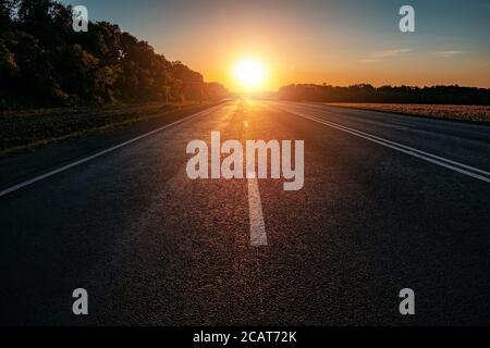 Abendsonne über der Asphaltstraße bei Sonnenuntergang Stockfoto
