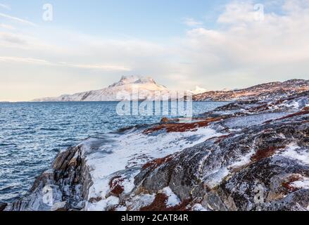 Tiefgefrorene Tundralandschaft mit kaltem grönländischen Meer und schneebeeten Sermitsiaq-Bergen im Hintergrund, nahe der Stadt Nuuk, Grönland Stockfoto