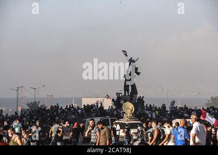 Beirut, Libanon, 8. August 2020. Demonstranten schwenken Flaggen von der Spitze der Statue des Märtyrerplatzes, während Libanesen nach einer katastrophalen Explosion auf die Straße gehen, bei der mehr als 6000 verletzt, über 150 getötet und große Teile der Hauptstadt dezimiert wurden. Sie beschuldigen ihre Regierung wegen unverantwortlicher Negativität bei der Lagerung der 2750 Tonnen hochexplosiven Ammoniumnitrats, die im Hafen von Beirut explodiert sind, ungefährlich in einem bevölkerten Gebiet. Elizabeth Fitt Kredit: Elizabeth Fitt/Alamy Live News Stockfoto