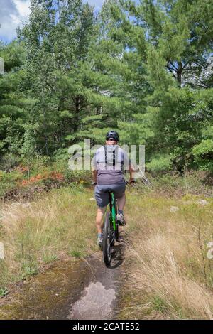 Ein pensionierter Mann, der durch einen Felspfad radeln kann Ontario Stockfoto