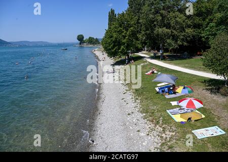Sipplingen Am Bodensee, Deutschland. August 2020. Sonnenanbeter liegen an der Uferpromenade am Bodensee unter ihren Sonnenschirmen. Die Behörden appellieren an Touristen, sich an die Regeln der Entfernung zu halten. (Aufgenommen mit hohem Stativ) Quelle: Felix Kästle/dpa/Alamy Live News Stockfoto
