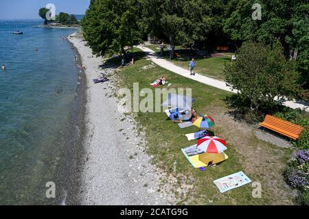 Sipplingen Am Bodensee, Deutschland. August 2020. Sonnenanbeter liegen an der Uferpromenade am Bodensee unter ihren Sonnenschirmen. Die Behörden appellieren an Touristen, sich an die Regeln der Entfernung zu halten. (Aufgenommen mit hohem Stativ) Quelle: Felix Kästle/dpa/Alamy Live News Stockfoto