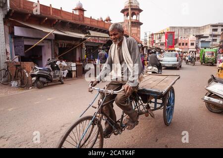 Agra / Indien - Februar 12, 2020: Menschen und Fahrzeuge auf belebten Straße vor rötlichen Mauern des berühmten Jama Masjid Stockfoto