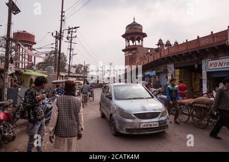 Agra / Indien - Februar 12, 2020: Menschen und Fahrzeuge auf belebten Straße vor rötlichen Mauern des berühmten Jama Masjid Stockfoto