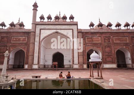 Agra / Indien - 12. Februar 2020: Zwei Hindu-Frauen sprechen am Pool im großen Innenhof der Jama-Moschee Stockfoto