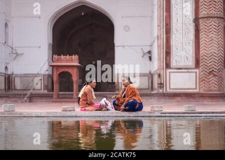 Agra / Indien - 12. Februar 2020: Zwei Hindu-Frauen sprechen am Pool im großen Innenhof der Jama-Moschee Stockfoto