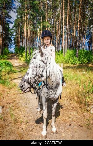 Nettes Mädchen auf einem weißen Pferd mit schwarzen Flecken Stockfoto