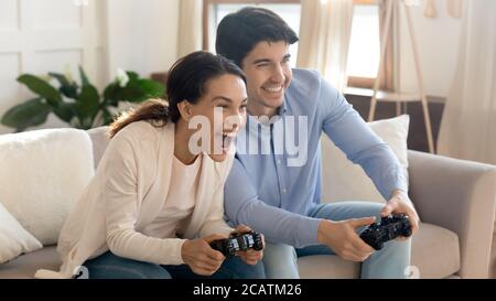 Emotional positive junge liebevolle Familie Paar spielen online-Videospiele. Stockfoto