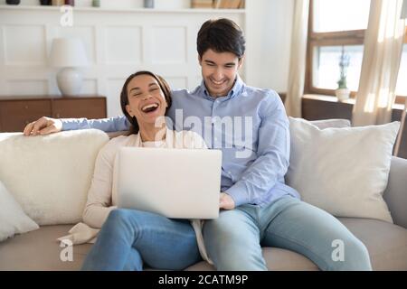 Emotional liebevolles junges Paar, das lustige Videos auf dem Computer ansieht. Stockfoto