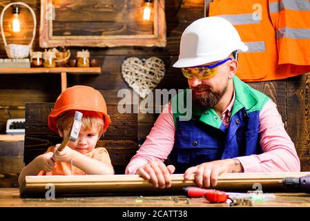 Vater und Sohn hämmern Nägel mit einem Hammer in ein Holzbrett. Glückliche Vaterschaft. Stockfoto