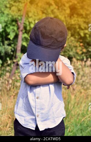 Trauriger weinender kleiner Junge bedeckt sein Gesicht mit Händen Outdoor Stock Bild. Stockfoto