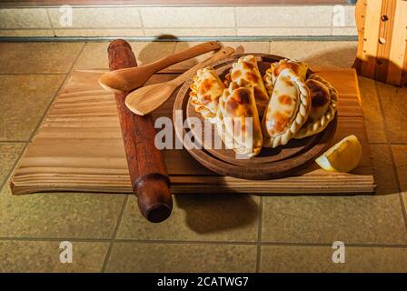 Holztisch mit frischen, hausgemachten Empanadas (detaillierte Nahaufnahme; selektive Fokus) Stockfoto