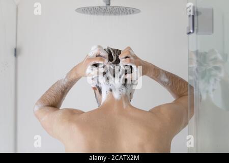 Rückansicht junger Mann Haare waschen, im Badezimmer stehen Stockfoto