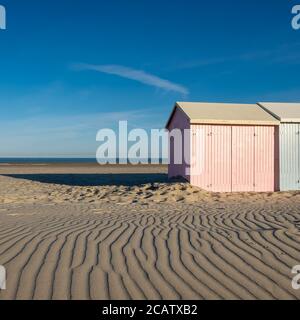 Sandmuster führen zu pastellfarbenen Strandhütten Stockfoto