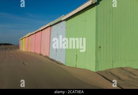 Pastellfarbene Strandhütten Reihen sich am einsamen Strand von Berck in Frankreich aneinander. Stockfoto