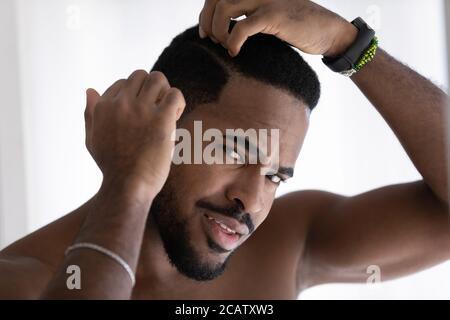 Nahaufnahme ängstlicher afroamerikanischer Mann, der den Kopf berührt und die Haare kontrolliert Stockfoto