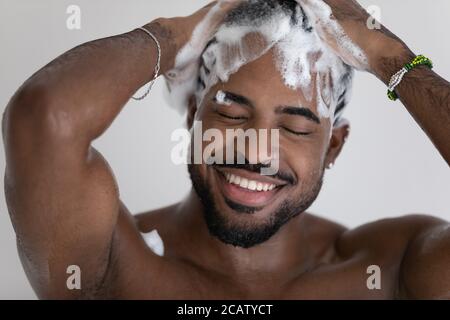 Nahaufnahme lächelnder afroamerikanischer Mann, der Haare mit Shampoo wäscht Stockfoto