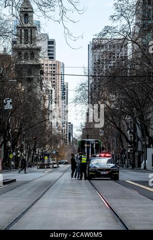 Melbourne, Australien am 9. August 2020 stellt ein Polizeibeamter der Victoria Police Highway zwei Prädestinationen in Bezug auf die Beschränkungen der Stufe 4 in Frage, nachdem er sie mitten in der Collins Street in Melbourne angehalten hat. Kredit: Michael Currie/Alamy Live Nachrichten Stockfoto