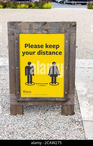 Gelb und schwarz 2m soziale Distanzierung Erinnerungszeichen bei RHS Garden, Wisley, Surrey Stockfoto