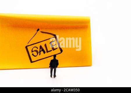 Miniatur Figur posierte als Geschäftsmann Blick auf Verkauf Zeichen Tag handgezeichnet auf Klebstoff Papier Hinweis, E-Commerce-Konzept Bild Stockfoto