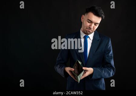 Porträt eines Geschäftsmanns mit blauem Business-Anzug und Krawatte Leere Brieftasche wird auf schwarzem Hintergrund mit Kopierplatz isoliert angezeigt Werbebereich Stockfoto